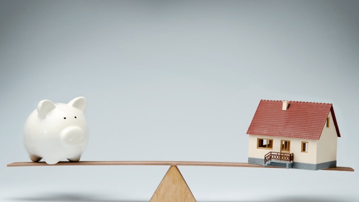  a piggy bank and toy house on a balance scale