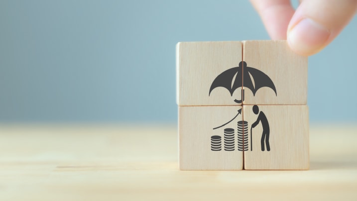 Wooden cubes with retirement assurance symbol standing on table