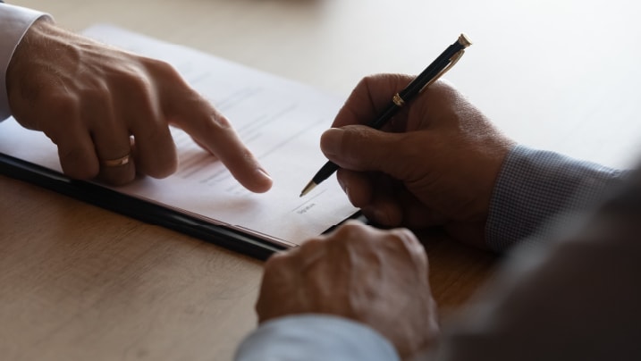 lawyer pointing at paper for businessman signing contract.