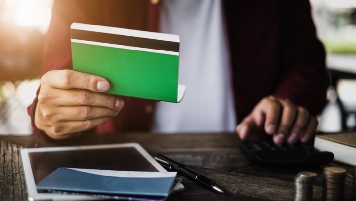 man holding saving account passbook with calculator on desk