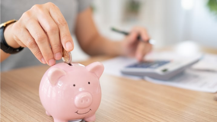 person putting coin in piggy bank for saving